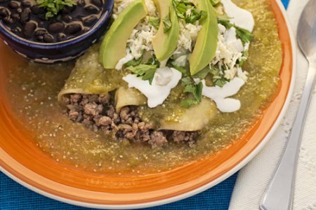 Enchiladas Verdes con Carne Molida servidas con frijoles